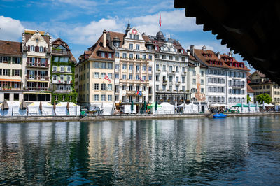 Buildings by river against sky in city