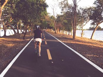 Rear view of woman riding bicycle on road