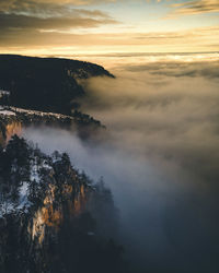 Scenic view of fog against sky during sunset