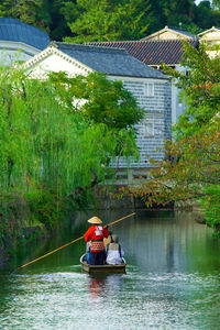 Rear view of men sitting on boat in river