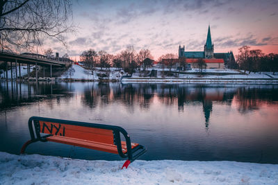 Built structure by lake against sky during winter