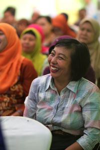 Smiling woman looking away while sitting in audience