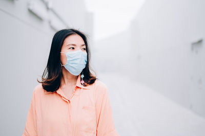 Portrait of young woman standing against wall