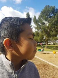 Close-up of boy with closed eyes against sky