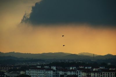 Silhouette buildings in city against sky during sunset