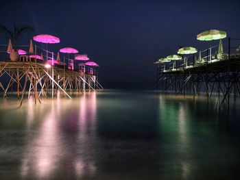 Seaside jetty with illuminated umbrellas at dusk. cannes france