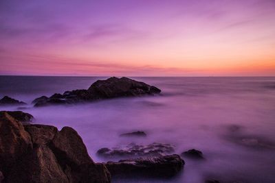 Scenic view of rocks on sea during sunset