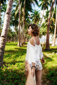 Full length of young woman standing on palm tree