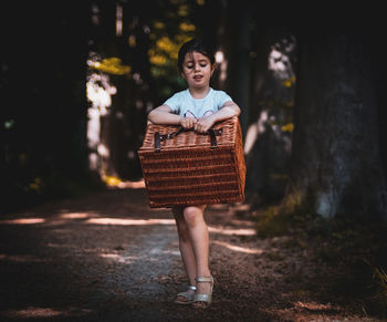 Little girl with a wicker basket in the forest.