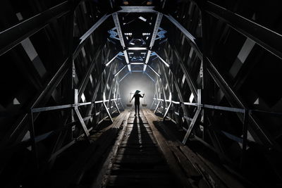 Rear view of man walking on footbridge