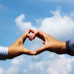 Cropped hands of couple making heart shape