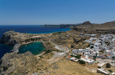 High angle view of town by sea against clear blue sky