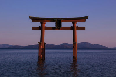 Lifeguard hut on sea against clear sky during sunset