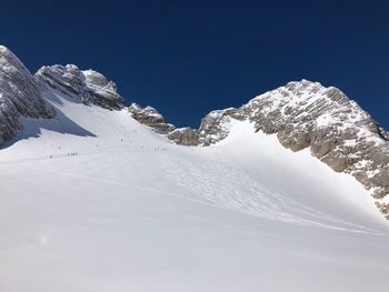 Low angle view of snowcapped mountain against clear blue sky