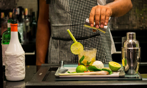 Midsection of bartender preparing cocktail