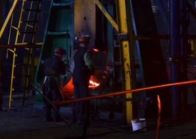 People standing by illuminated fire at night