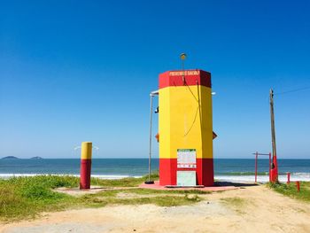 Lifeguard hut on beach against clear blue sky