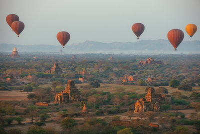 Hot air balloons flying over landscape against sky