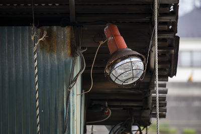 Low angle view of lighting equipment hanging on rope against building