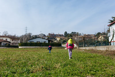 Rear view of children walking on field