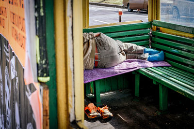 Low section of man sleeping on bench