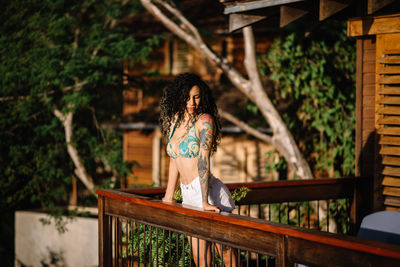 Woman sitting on railing against plants