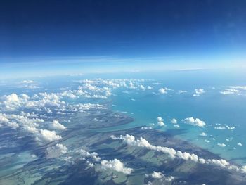 Aerial view of sea and landscape against blue sky