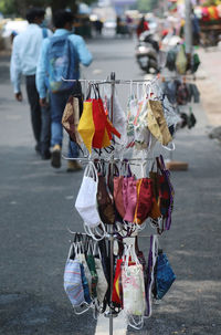 Designer face mask seen for sale at a street market on rode side as people walking on road 