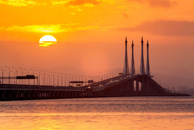 View of suspension bridge in sea during sunset