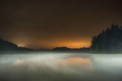 Long exposure of fog over lake at mt hood national forest against sky during sunset