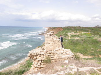 People standing on shore by sea against sky