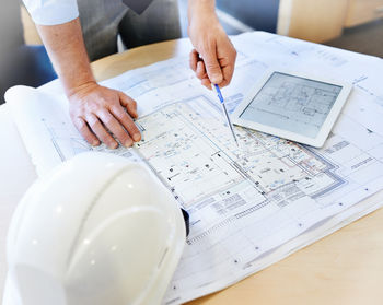 Midsection of businessman working on blueprint