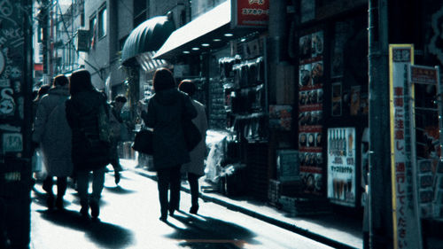 Rear view of people walking on street in city