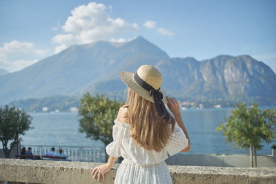 Rear view of woman looking at sea against mountains