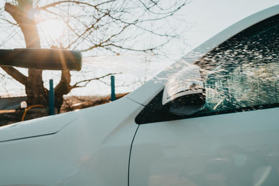 Manual car wash with jet of high pressure water. worker washes white automobile outside 