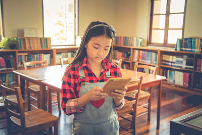 Girl using digital tablet in library