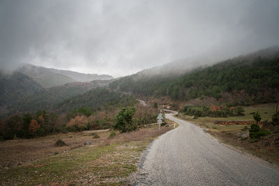 Road leading towards mountains against sky