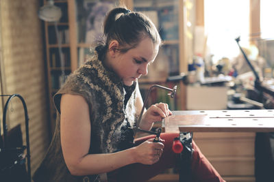 Master in the home workshop saws out a piece of copper metal with a jigsaw, concept creativity l