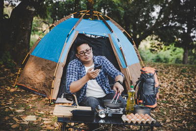 Man on camping holiday frying egg in pan