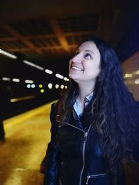 Smiling woman looking up in illuminated city