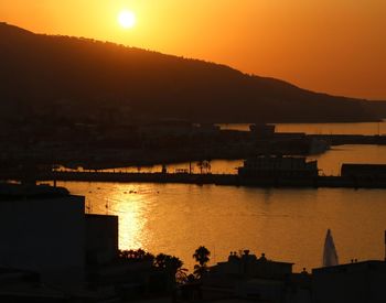 Silhouette city against orange sky