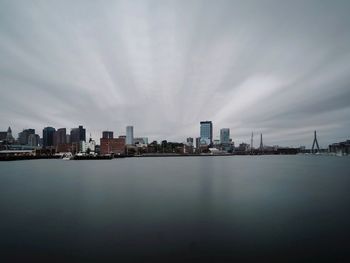 Sea by buildings against sky in city