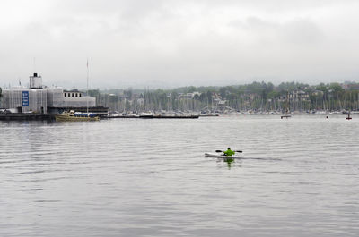 Rear view of man kayaking in river against sky