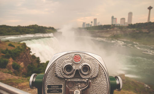 Close-up of coin-operated binoculars against cityscape