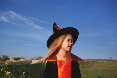 Woman wearing hat standing on field against sky