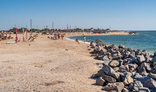 Group of people on beach against clear sky