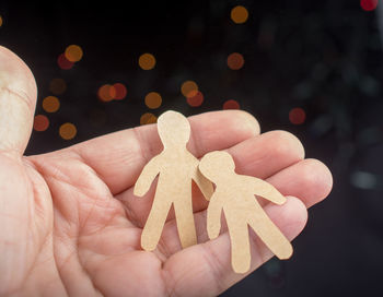 Close-up of hand holding human cardboard cutouts