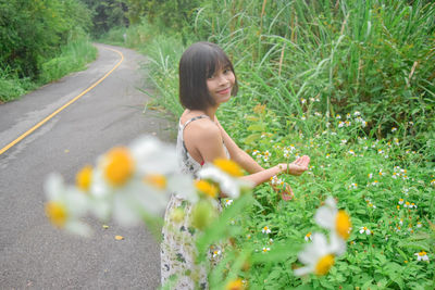 Portrait of woman on road amidst flowering plants