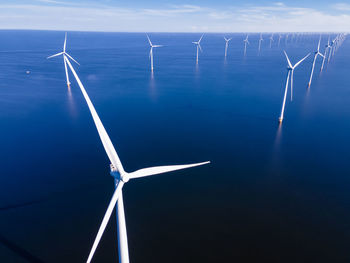 Wind turbines in sea against sky