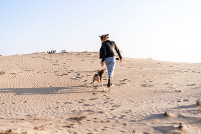 Full length rear view of man walking on desert